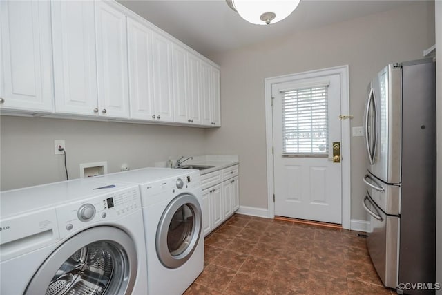 clothes washing area featuring sink, washing machine and dryer, and cabinets