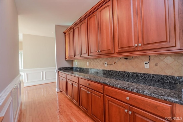 kitchen with tasteful backsplash, dark stone counters, and light hardwood / wood-style flooring