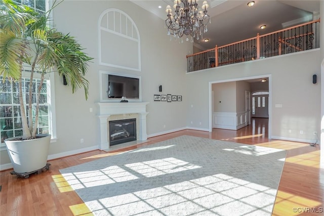 unfurnished living room featuring hardwood / wood-style flooring, a towering ceiling, and a notable chandelier