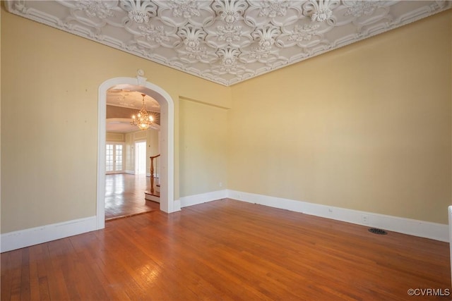 empty room with hardwood / wood-style flooring and a notable chandelier