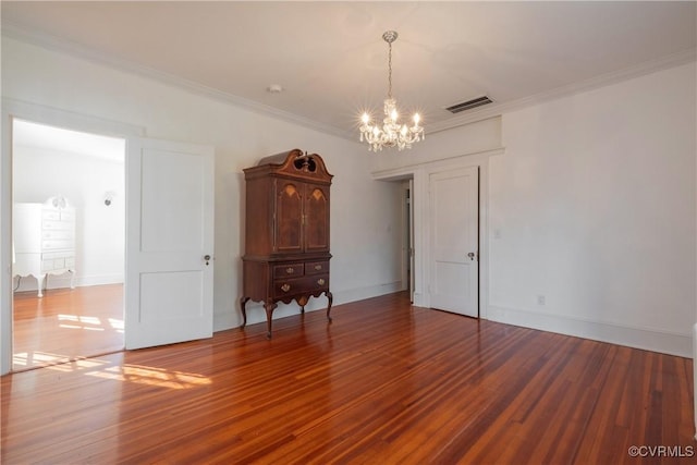 empty room with ornamental molding, hardwood / wood-style floors, and a chandelier