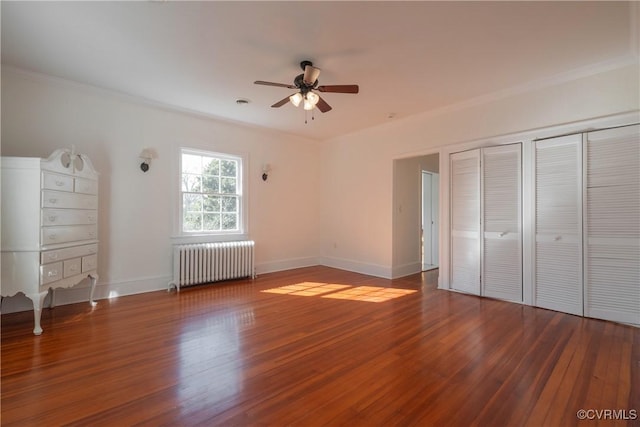 unfurnished bedroom with radiator, hardwood / wood-style floors, ceiling fan, and a closet