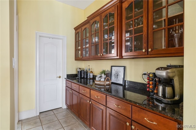 bar featuring light tile patterned floors and dark stone counters