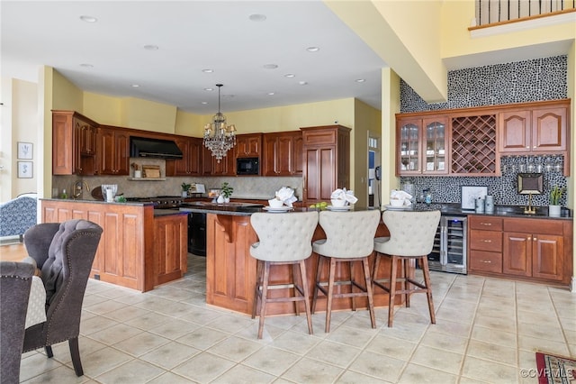 kitchen featuring light tile patterned flooring, decorative light fixtures, range hood, black microwave, and beverage cooler