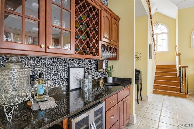 bar with decorative light fixtures, sink, dark stone countertops, wine cooler, and decorative backsplash