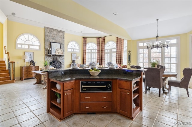 kitchen featuring light tile patterned floors, hanging light fixtures, a notable chandelier, a fireplace, and a kitchen island