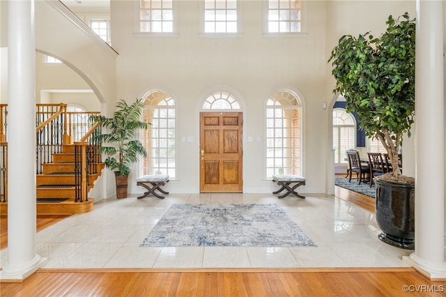 entryway with decorative columns, a high ceiling, and light tile patterned floors