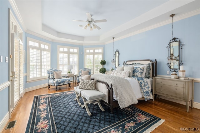 bedroom featuring hardwood / wood-style flooring, a raised ceiling, and ornamental molding