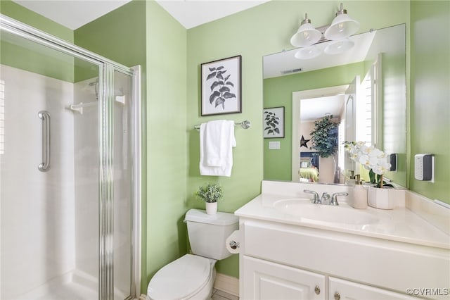 bathroom featuring vanity, a shower with door, and toilet