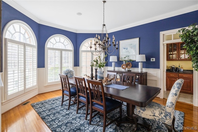 dining room featuring crown molding, an inviting chandelier, and hardwood / wood-style floors