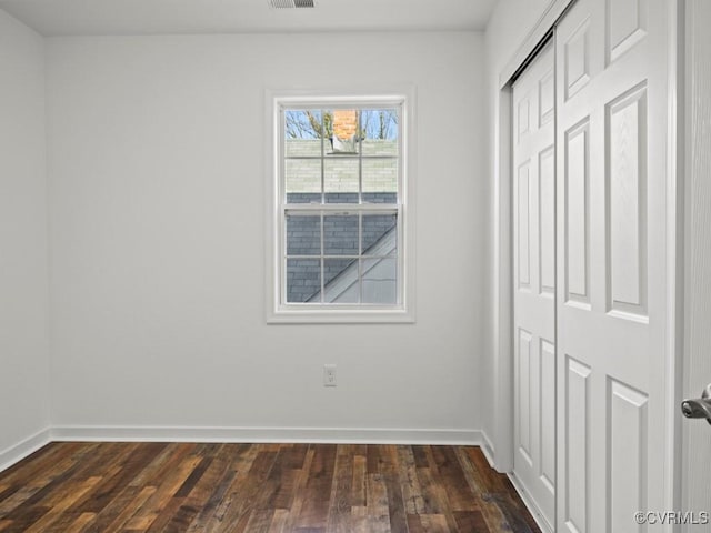 unfurnished bedroom with dark hardwood / wood-style flooring and a closet