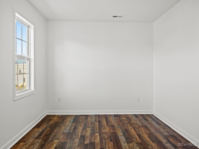 empty room with a healthy amount of sunlight and dark wood-type flooring