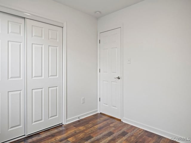 unfurnished bedroom featuring dark hardwood / wood-style flooring and a closet