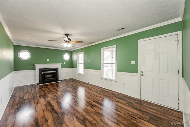 unfurnished living room with ceiling fan, ornamental molding, dark wood-type flooring, and a textured ceiling