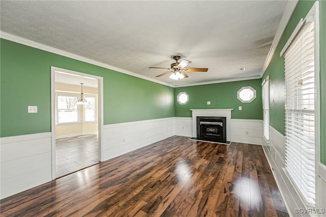 unfurnished living room with dark hardwood / wood-style flooring, ceiling fan, crown molding, and a textured ceiling