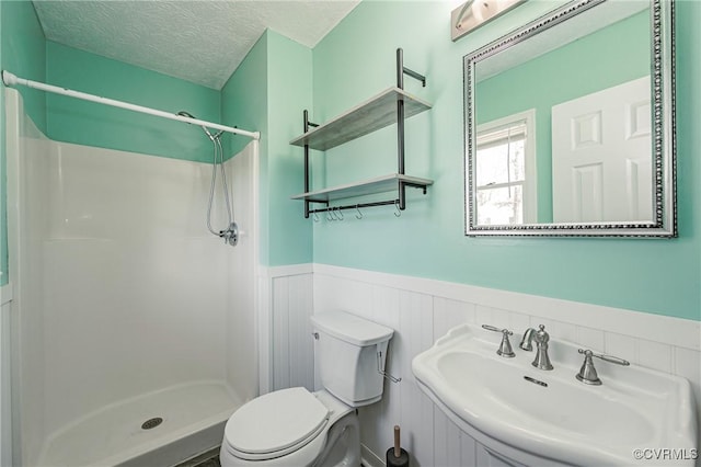 bathroom featuring toilet, sink, a textured ceiling, and a shower