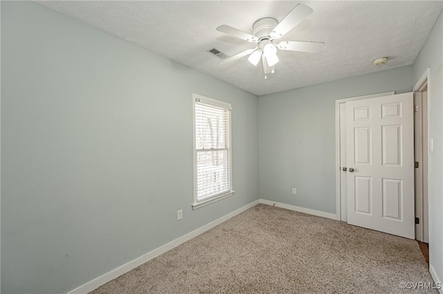 empty room with ceiling fan, carpet flooring, and a textured ceiling