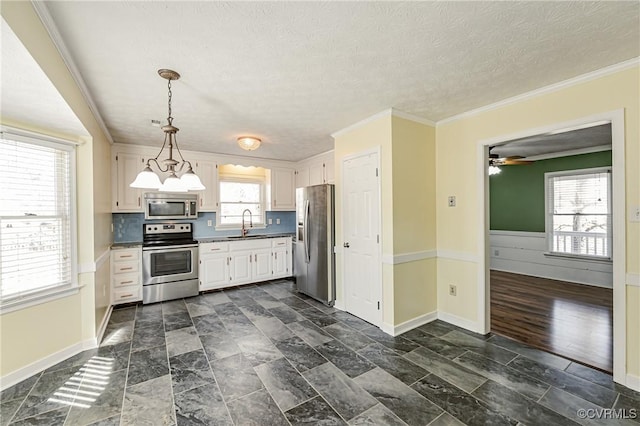 kitchen featuring sink, hanging light fixtures, a textured ceiling, ornamental molding, and appliances with stainless steel finishes