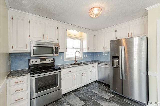 kitchen featuring sink, dark stone countertops, white cabinets, backsplash, and stainless steel appliances