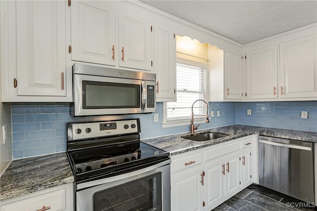 kitchen with sink, stainless steel appliances, dark stone counters, and white cabinets