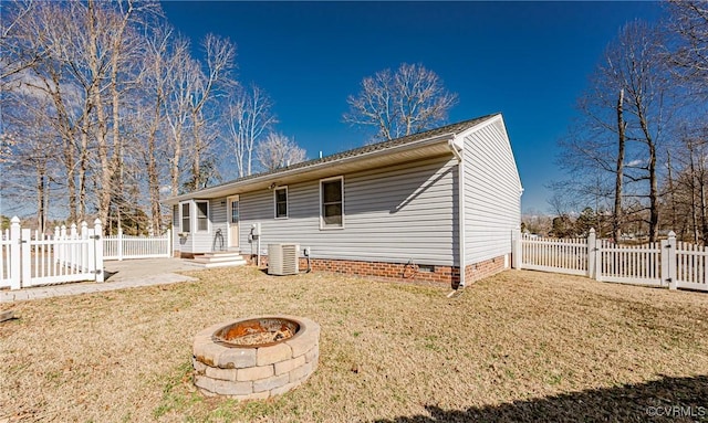 back of property featuring cooling unit, a fire pit, and a lawn