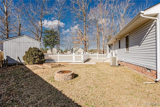 view of yard featuring central AC, a storage shed, and a fire pit