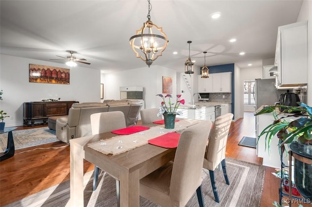 dining space featuring ceiling fan with notable chandelier, recessed lighting, and wood finished floors