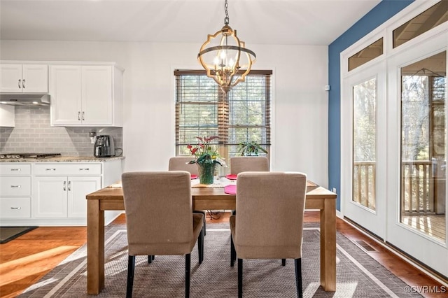 dining area featuring dark wood-style flooring, visible vents, and a notable chandelier