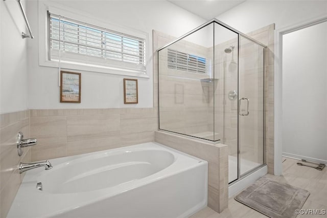 bathroom with a stall shower and a garden tub