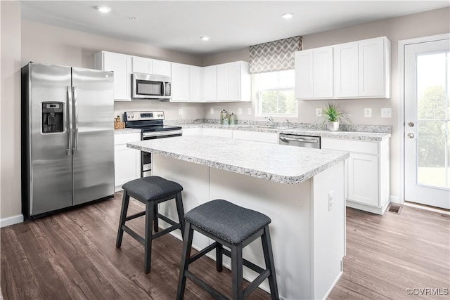 kitchen with sink, appliances with stainless steel finishes, a kitchen breakfast bar, a kitchen island, and white cabinets