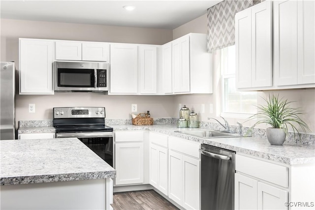 kitchen with dark hardwood / wood-style flooring, sink, stainless steel appliances, and white cabinets