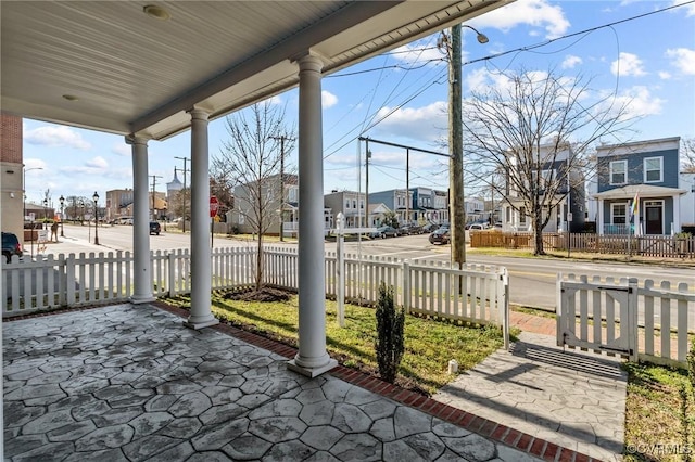 view of patio / terrace with a fenced front yard, a residential view, and covered porch