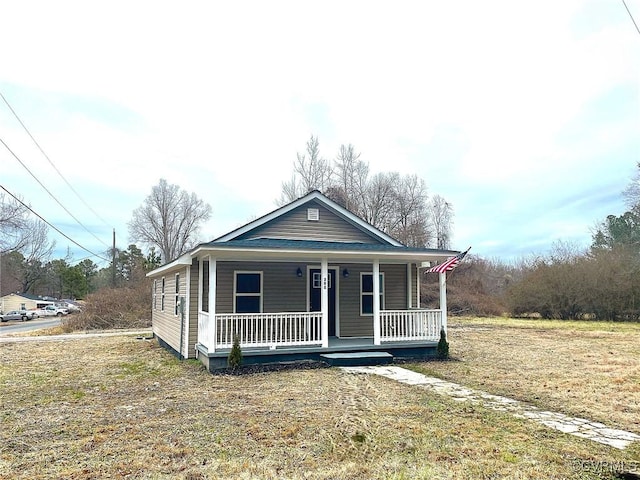 bungalow featuring covered porch and a front lawn