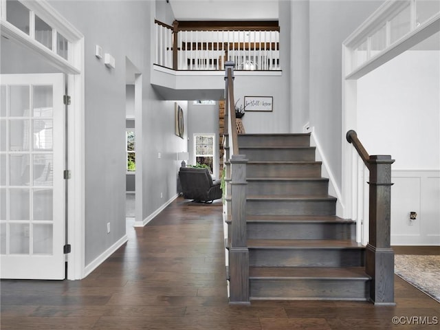 stairway with hardwood / wood-style flooring and a towering ceiling