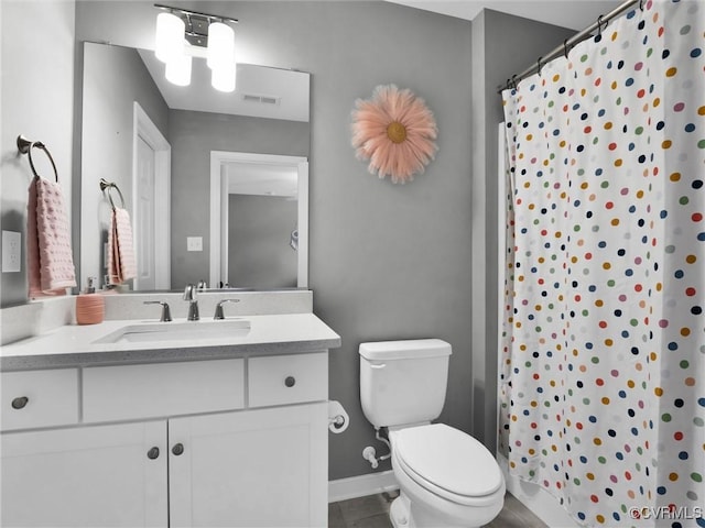 bathroom with tile patterned flooring, toilet, vanity, and walk in shower