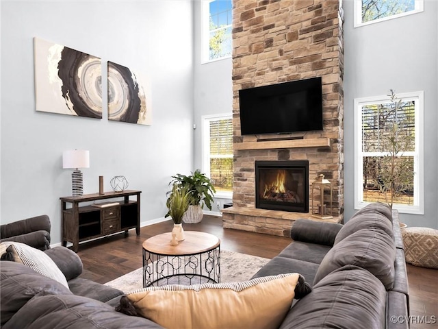 living room featuring dark hardwood / wood-style flooring, a towering ceiling, a fireplace, and plenty of natural light