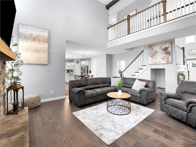 living room featuring dark wood-type flooring, a chandelier, and a high ceiling