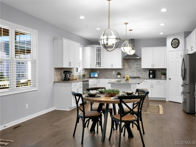 kitchen with white cabinetry, light stone counters, hanging light fixtures, stainless steel appliances, and backsplash