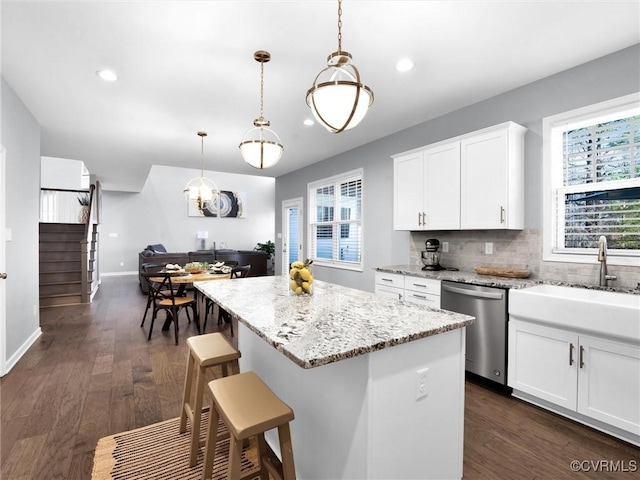 kitchen with hanging light fixtures, a center island, stainless steel dishwasher, and white cabinets