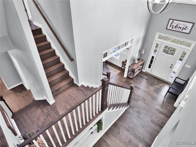 foyer entrance with a notable chandelier, dark hardwood / wood-style floors, and a high ceiling