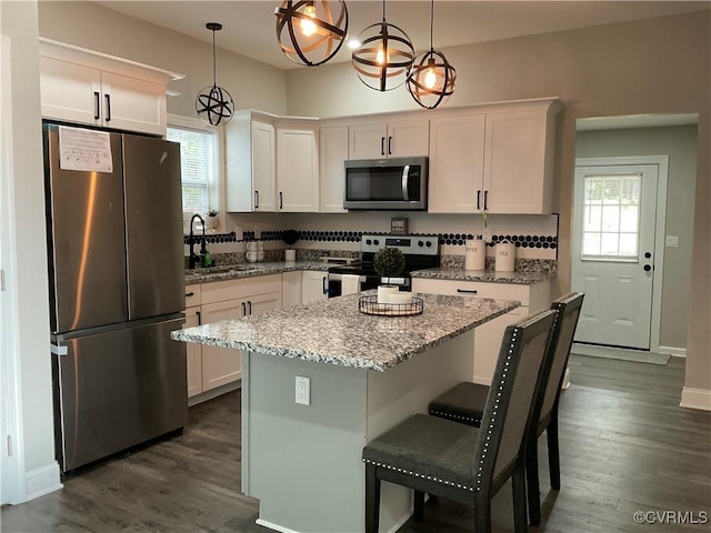 kitchen featuring a kitchen island, appliances with stainless steel finishes, pendant lighting, and white cabinets