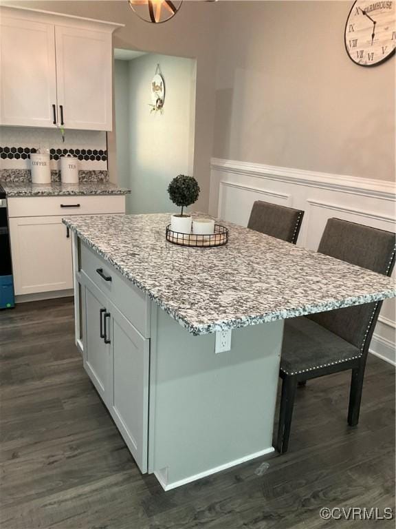 kitchen with white cabinetry, a kitchen island, and a kitchen bar