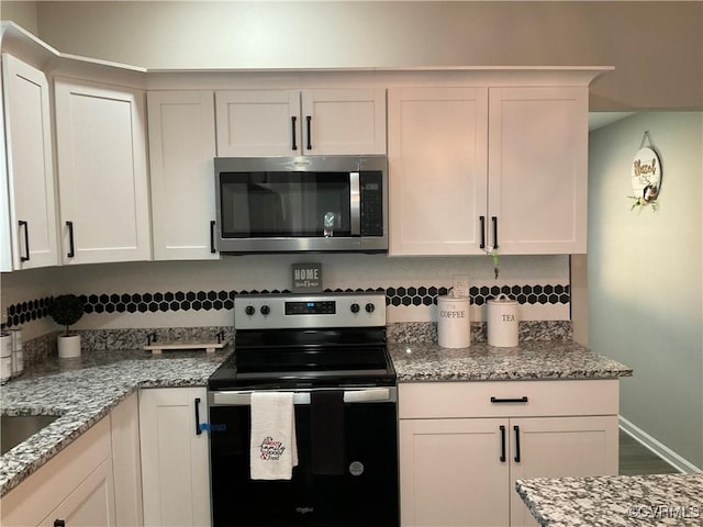 kitchen with white cabinetry, electric range oven, and light stone countertops