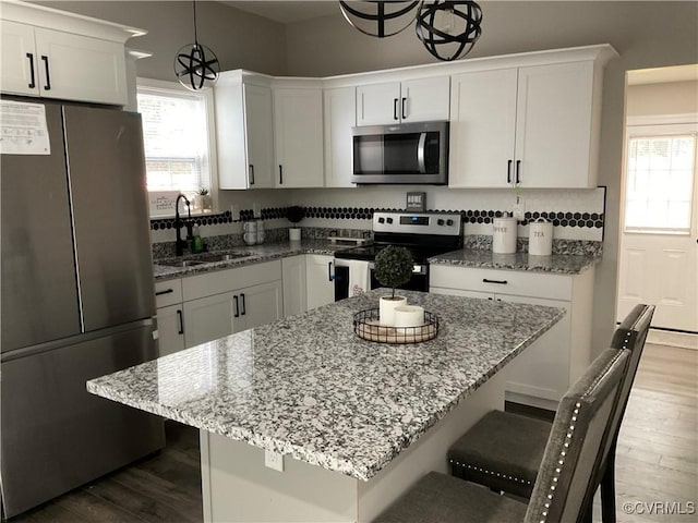 kitchen with hanging light fixtures, appliances with stainless steel finishes, sink, and white cabinets