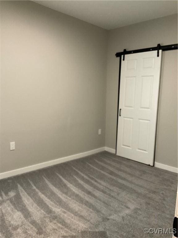 unfurnished bedroom with dark colored carpet and a barn door