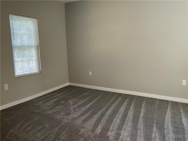 spare room featuring dark colored carpet