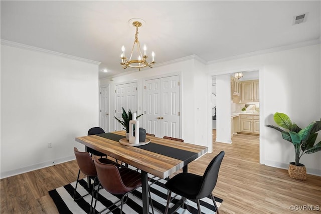 dining area with crown molding, an inviting chandelier, and light wood-type flooring