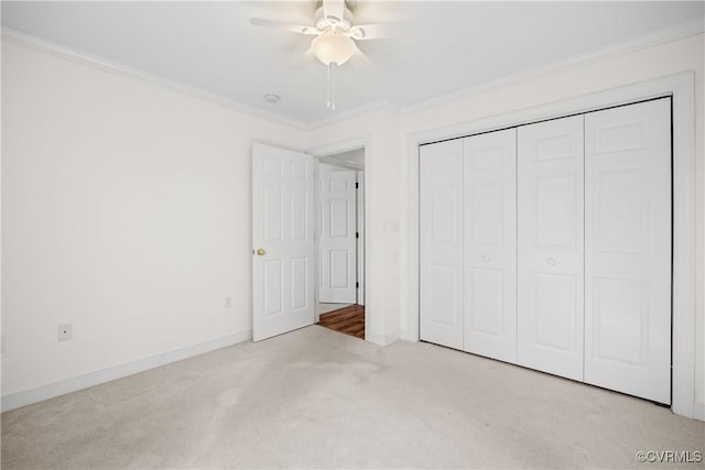 unfurnished bedroom with ceiling fan, light colored carpet, ornamental molding, and a closet