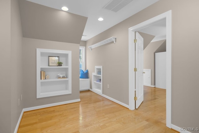 hallway with wood-type flooring and built in features