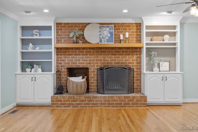 unfurnished living room with a brick fireplace, ornamental molding, and light wood-type flooring